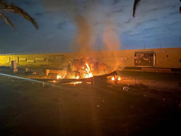 Burning debris are seen on a road near Baghdad International Airport
