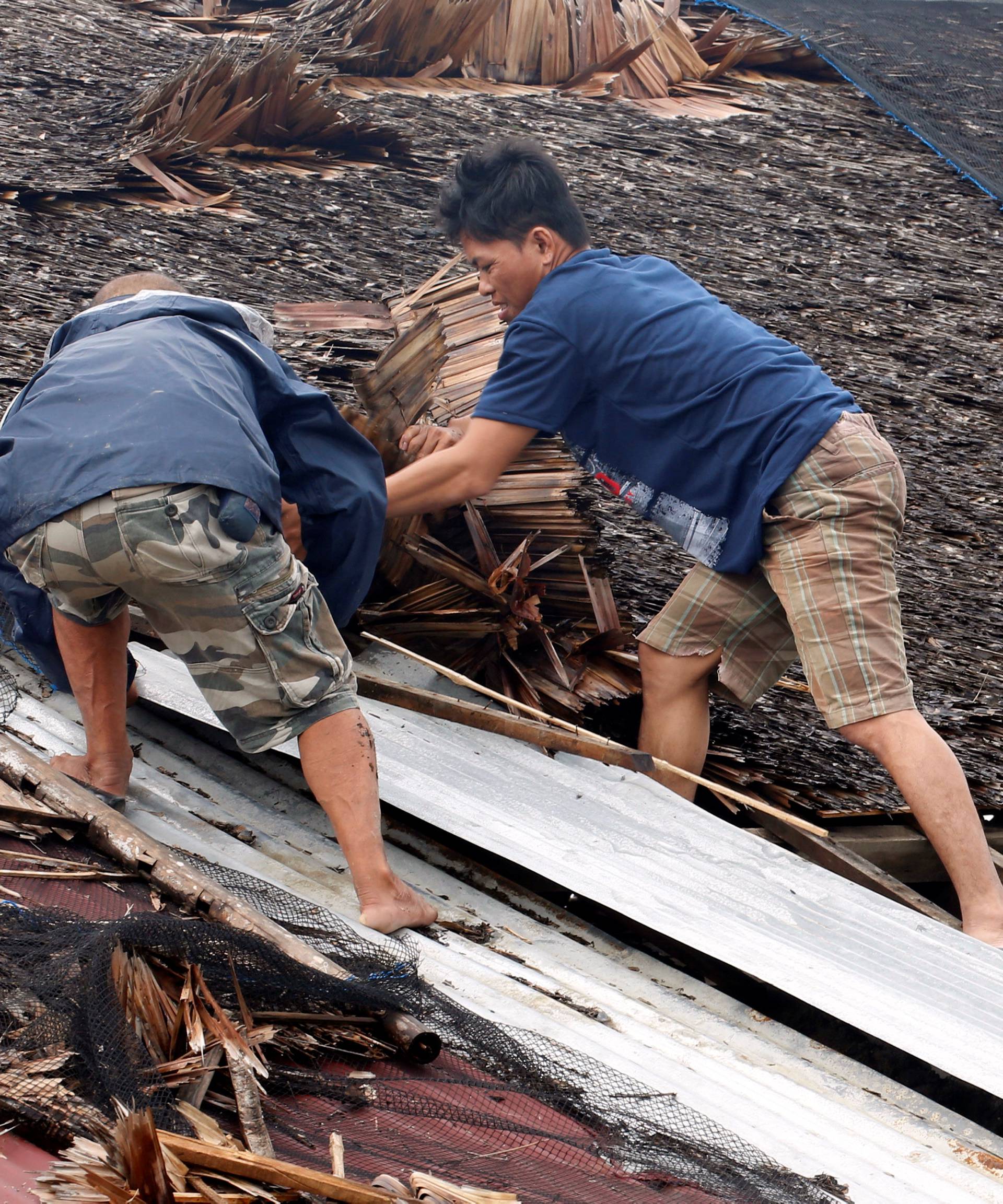 Residents fix their partially damaged roof after Typhoon Nock-Ten hit Mabini, Batangas
