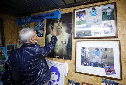A man touches a picture of Argentine soccer legend Diego Maradona in the Spanish Quarter of Naples after the announcement of his death, in Naples
