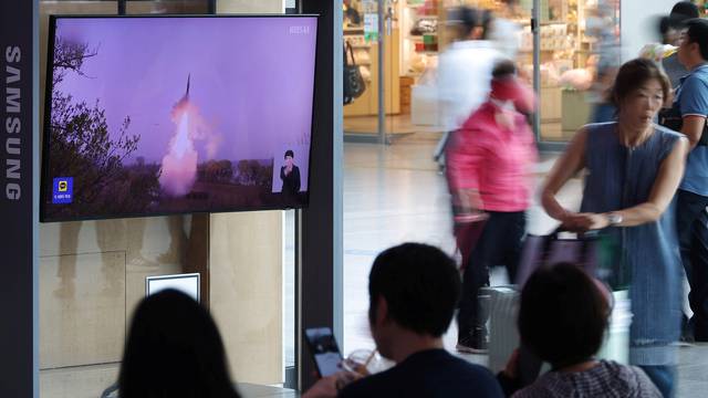 Passengers wait for their train in front of a TV broadcasting a news report on North Korea firing a ballistic missile off its east coast, at a railway station in Seoul