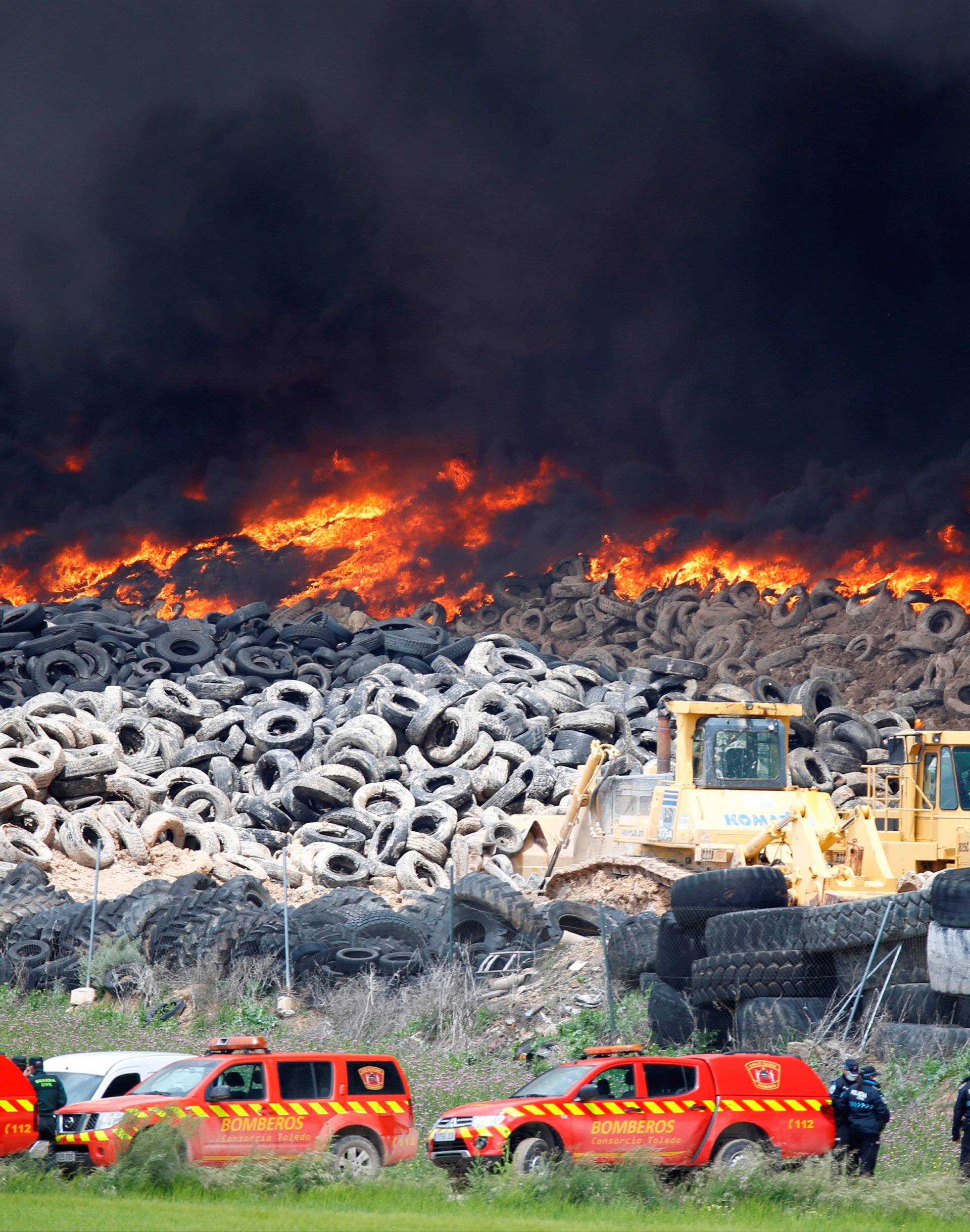 Emergency workers stand next to a fire at a tire dump near a residential development in Sesena, south of Madrid