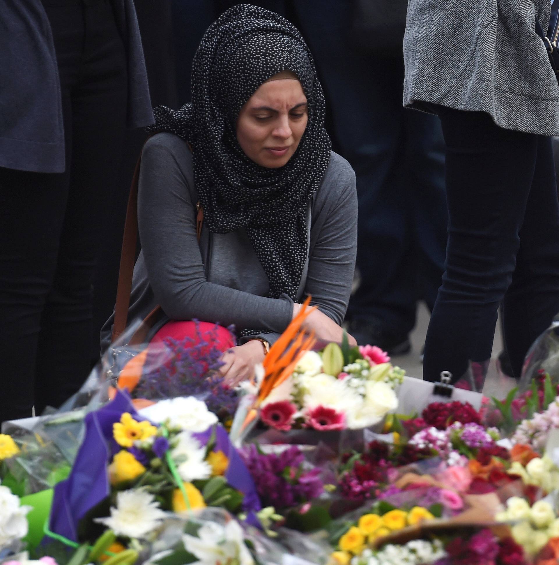 A woman reacts next to flowers left on the south side of London Bridge near Borough Market after an attack left 7 people dead and ozens of injured in London