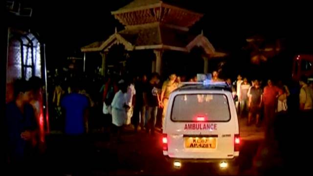 An ambulance is seen next to people after a fire broke out as people gathered for a fireworks display at a temple in Kollam, southern India