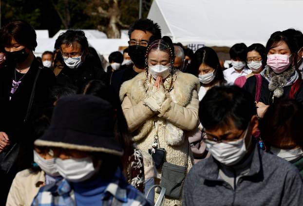 People pay a silent tribute to mourn the victims of the March 11, 2011 earthquake and tsunami, on the 11th anniversary of the events that killed thousands and set off a nuclear crisis, in Tokyo