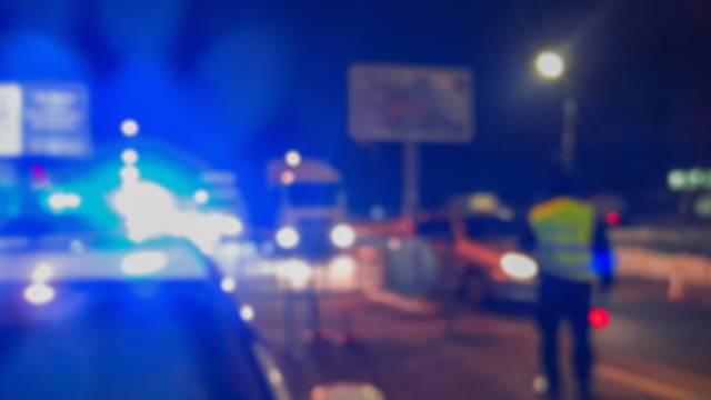 Unrecognizable blurry police car lights and police force officer on night road background, crime scene, night patrolling the city. Abstract  defocused image.