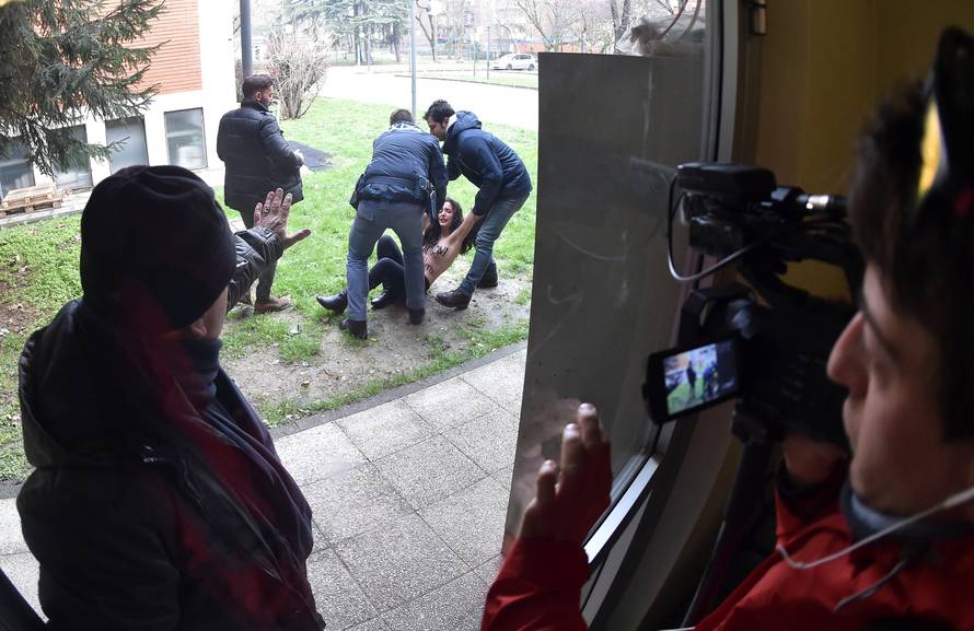 Italian policemen block an activist of women's rights group Femen in the polling station where Forza Italia party leader Silvio Berlusconi casted his vote in Milan
