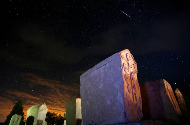 A meteor streaks past stars in the night sky above medieval tombstones in Radmilje near Stolac, south of Sarajevo