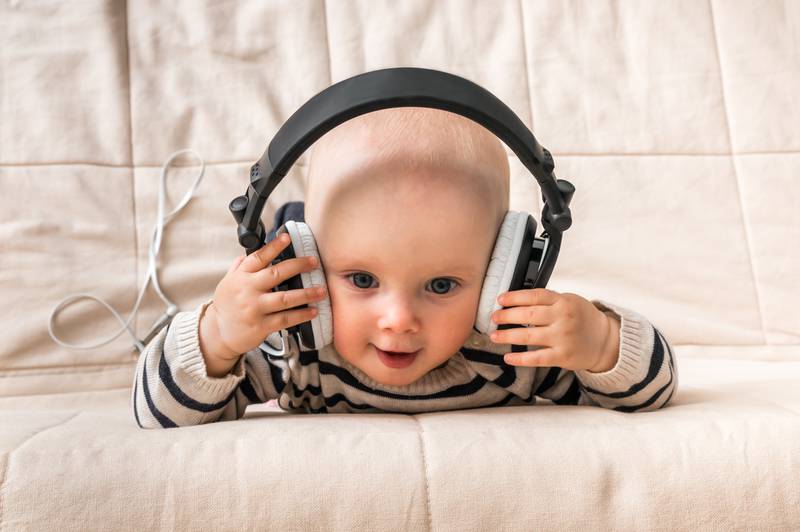 Cute baby with headphones listens to music at home