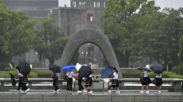 Visitors holding umbrellas struggle against heavy rains and winds caused by Typhoon Nanmadol in Hiroshima