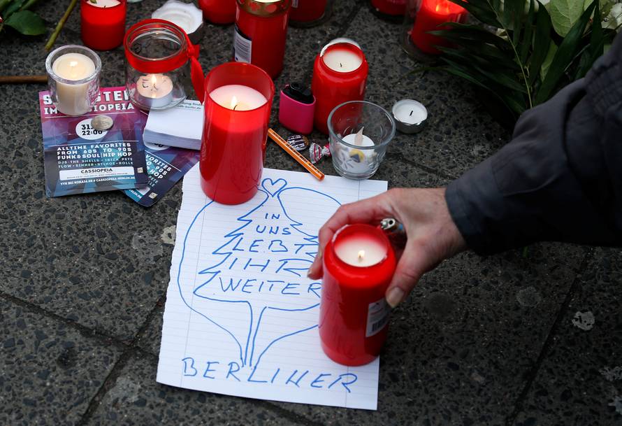 A man lights a candle near the scene where a truck ploughed into a crowded Christmas market in the German capital last night in Berlin
