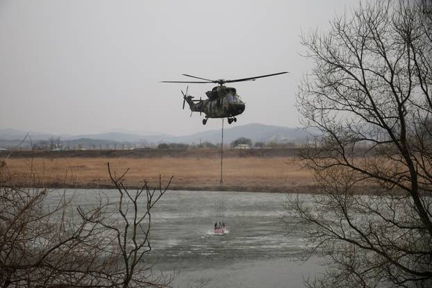 South Korean Army's Surion helicopter picks up water from a river during an operation as a wildfire burns, in Uiseong