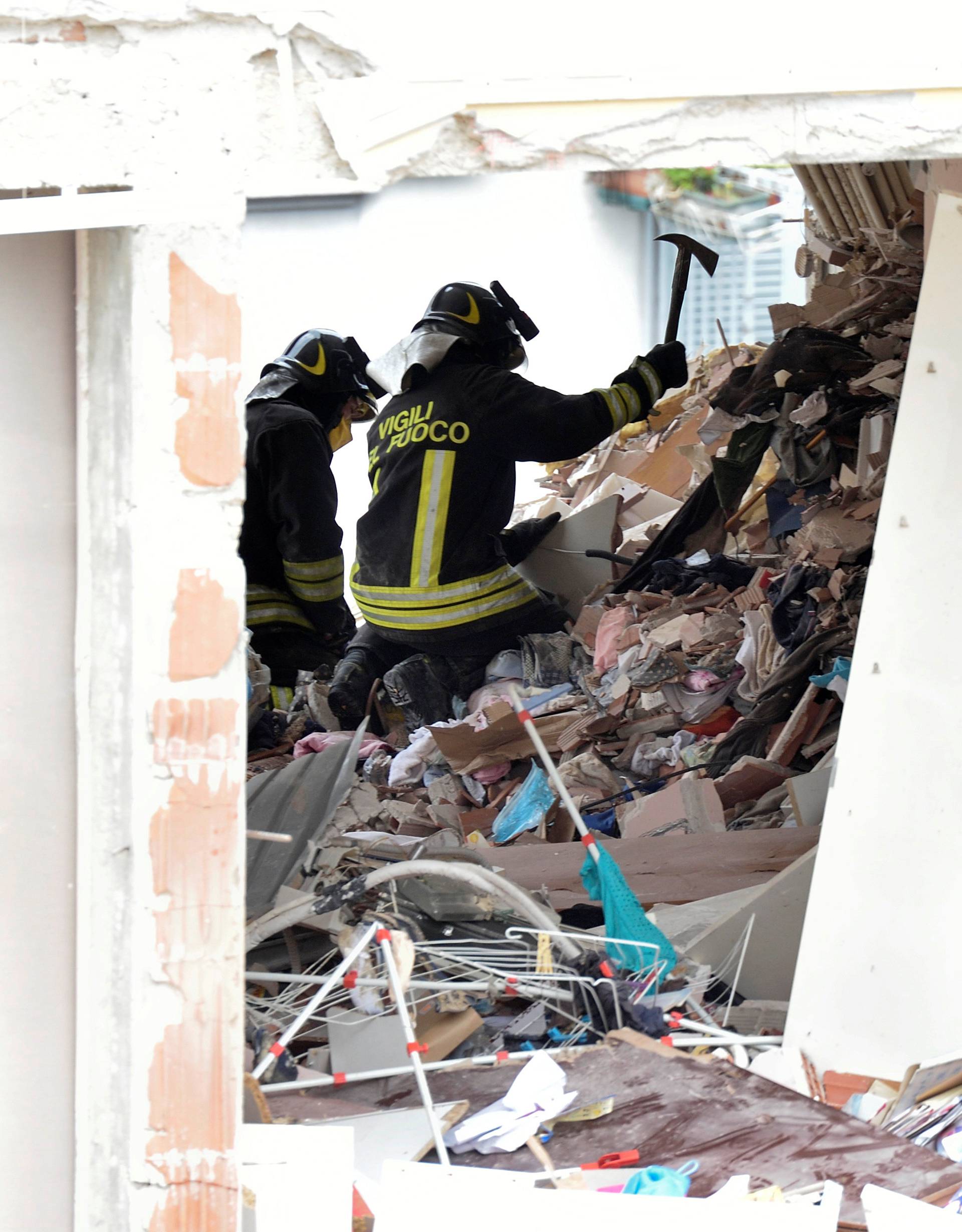 Italian firefighters work in the debris after a residential building partially collapsed on Sunday following an explosion in Milan