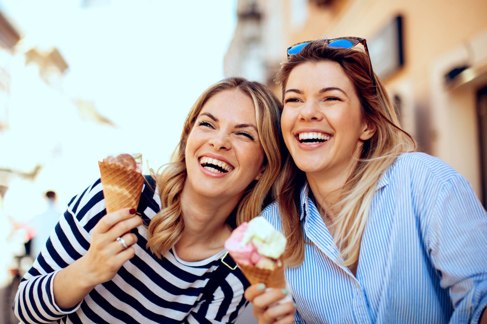 Two young women laughing and holding ice cream in hand