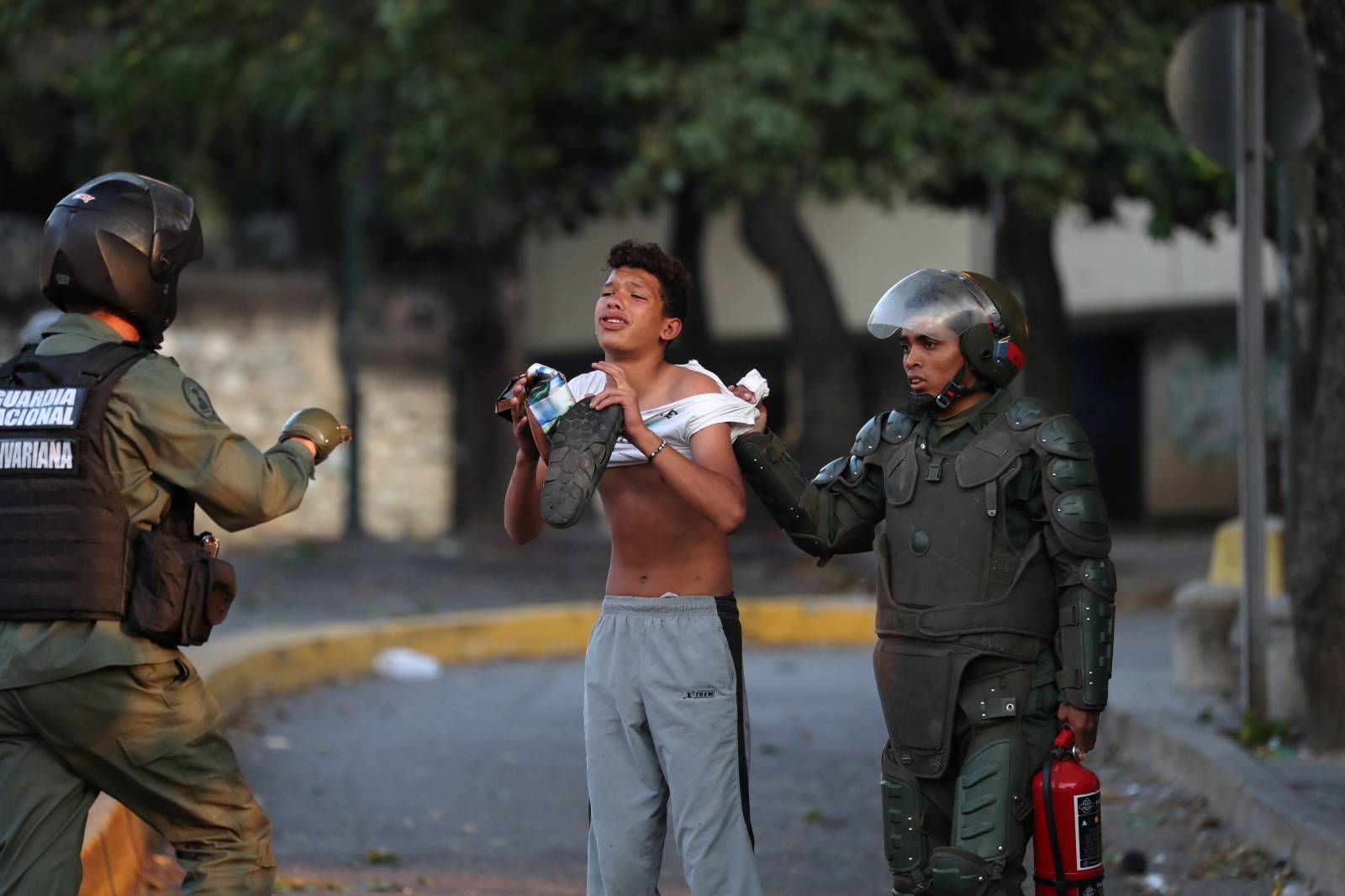 A youth reacts as he is detained by security forces after looting broke out during an ongoing blackout in Caracas
