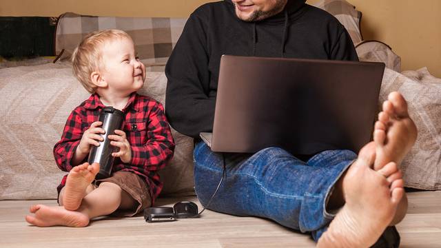 Young father working at home with computer and his child