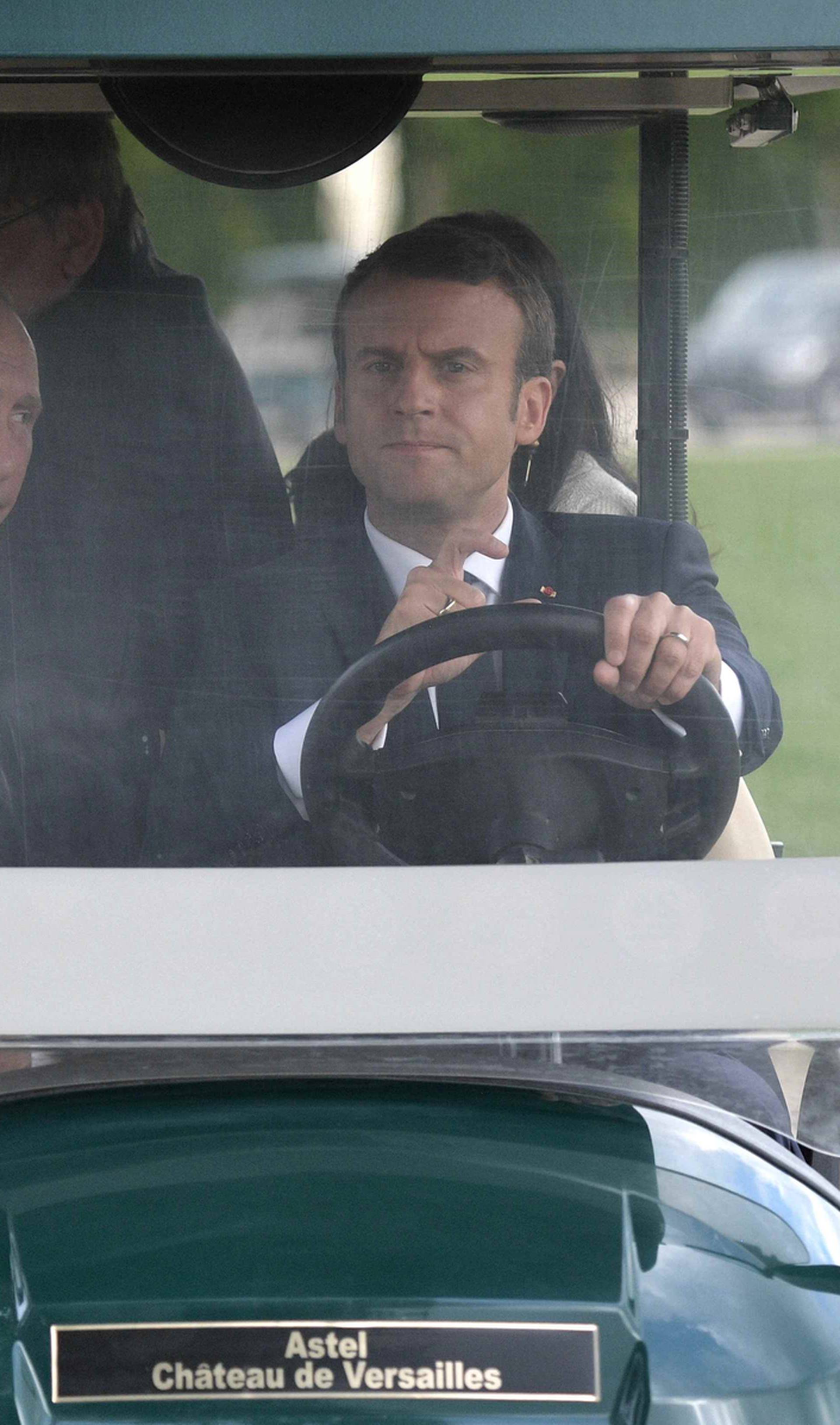French President Macron and Russian President Putin drive an electric golf car in the gardens of the Chateau de Versailles near Paris