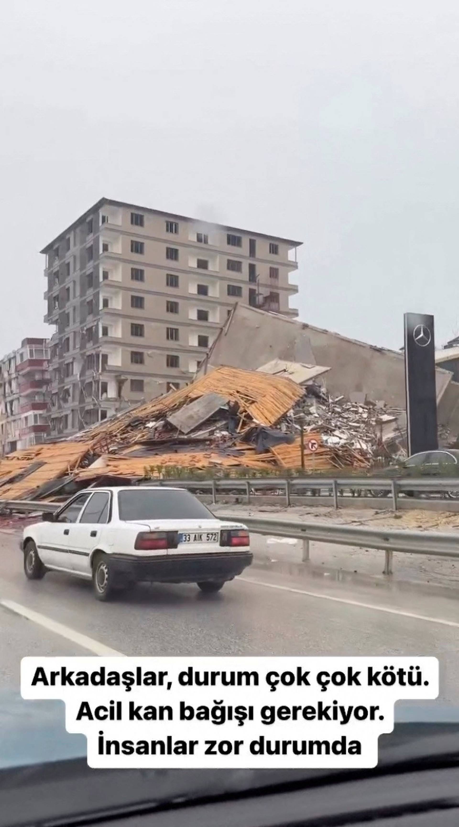 View of a collapsed building seen from a car following an earthquake in Hatay