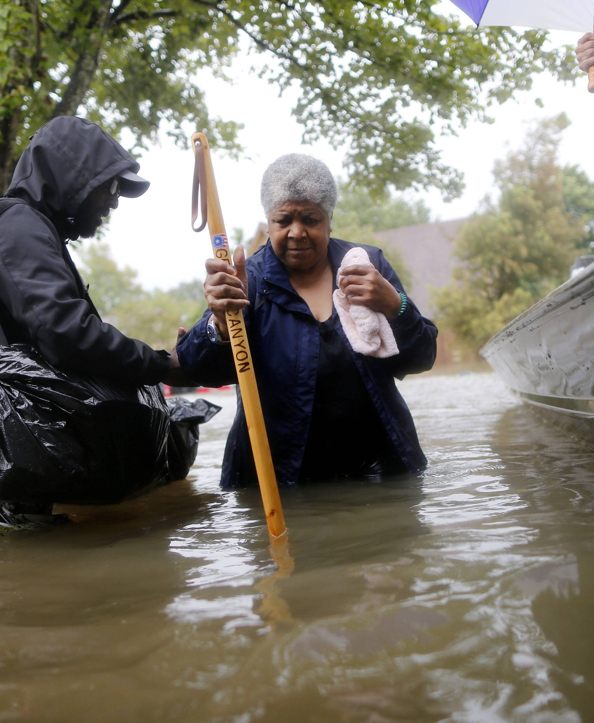 Andrew Mitchell helps his neighbor Beverly Johnson onto a rescue boat to escape the rising flood waters from Tropical Storm Harvey in Beaumont Place