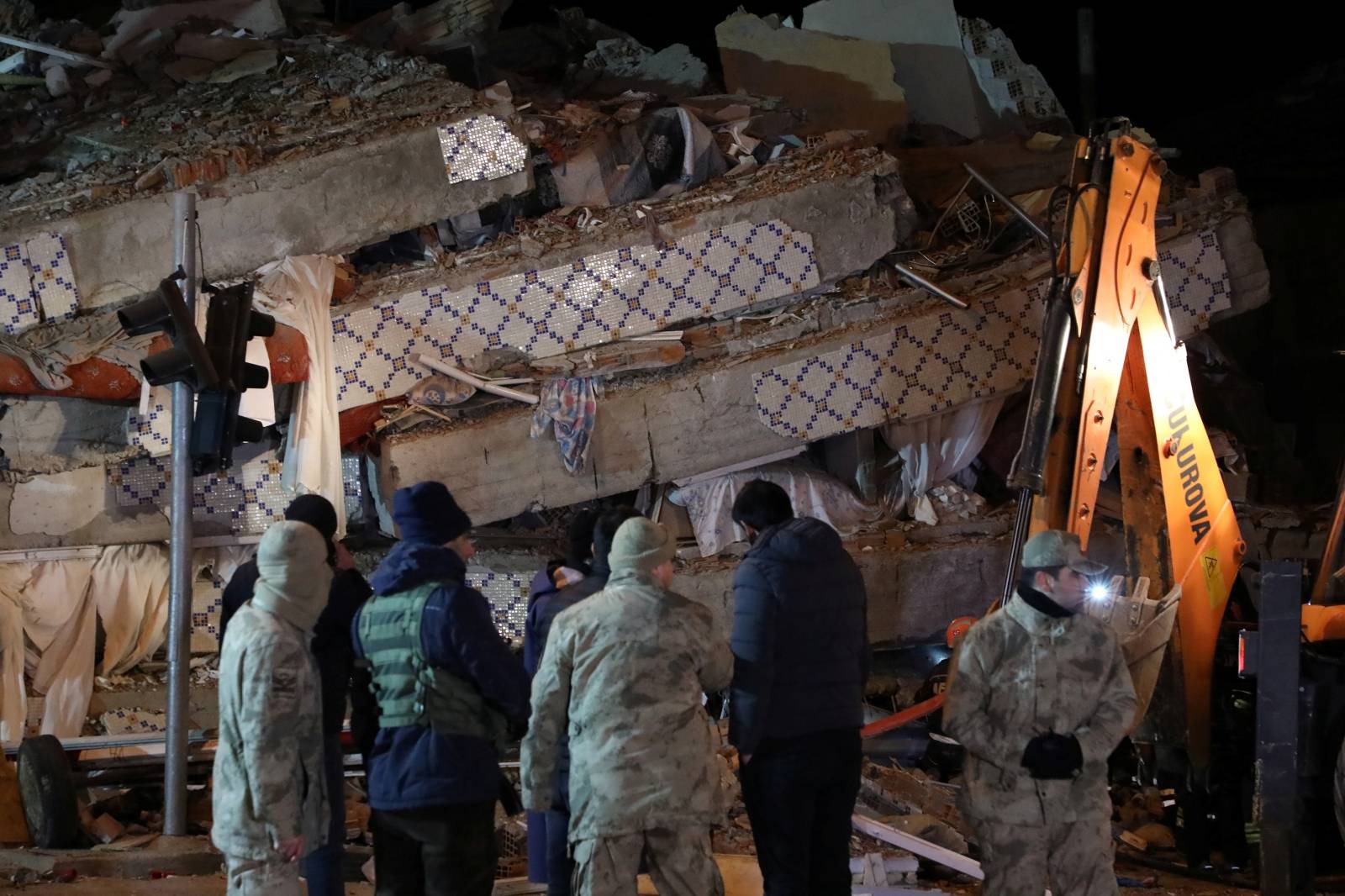 Turkish security forces stand guard outside a collapsed building after an earthquake in Elazig