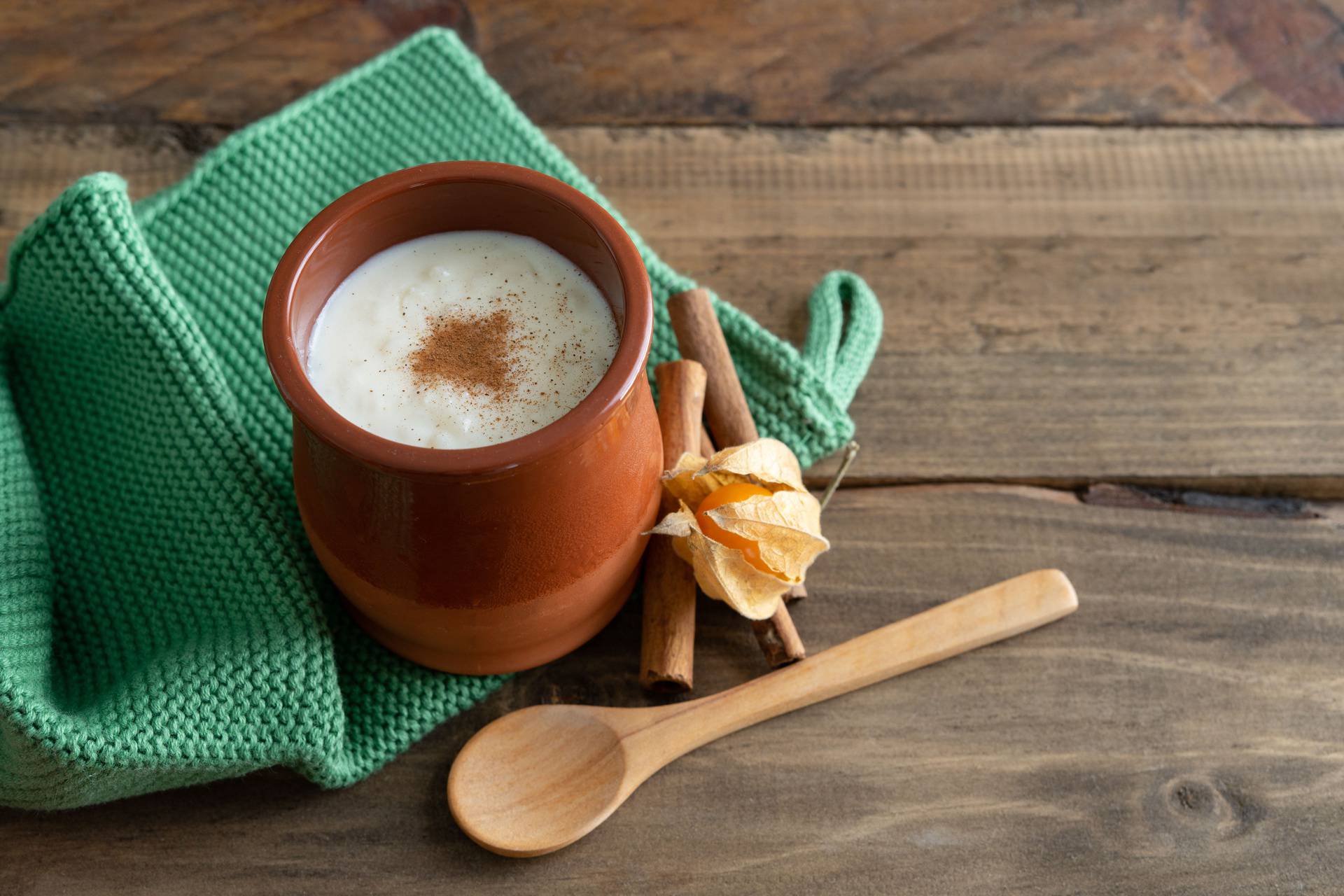 Bowls of rice pudding and cinnamon on a wooden background. Copy space.