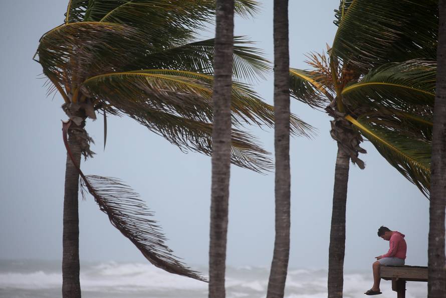 A man sits on a life guard tower as the wind blows at the beach in advance of Hurricane Irma's expected arrival in Hollywood, Florida