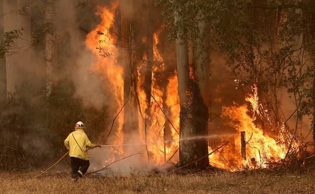 A Tuncurry fire crew member fights part of the Hillville bushfire south of Taree