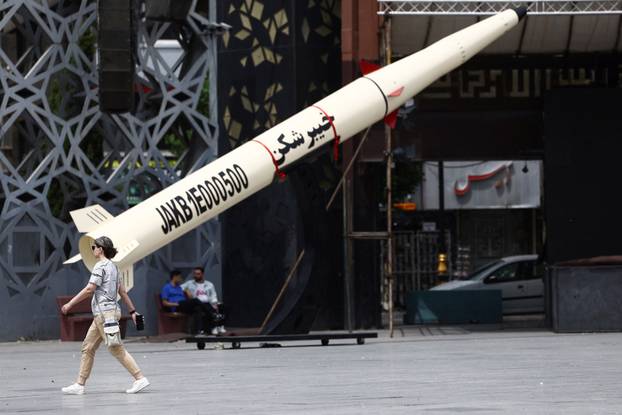 A woman walks next to a symbolic mockup of an Iranian missile in Tehran