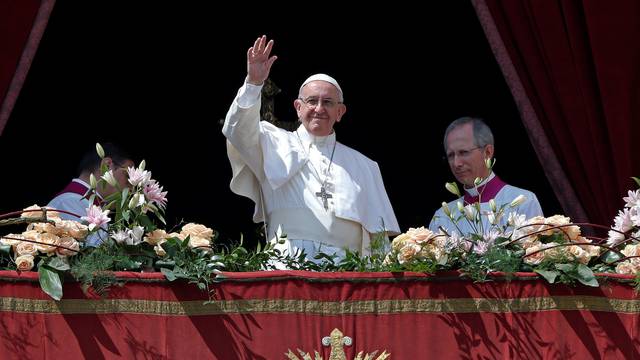 Pope Francis waves at the end of his "Urbi et Orbi" (to the city and the world) message from the balcony overlooking St. Peter's Square at the Vatican