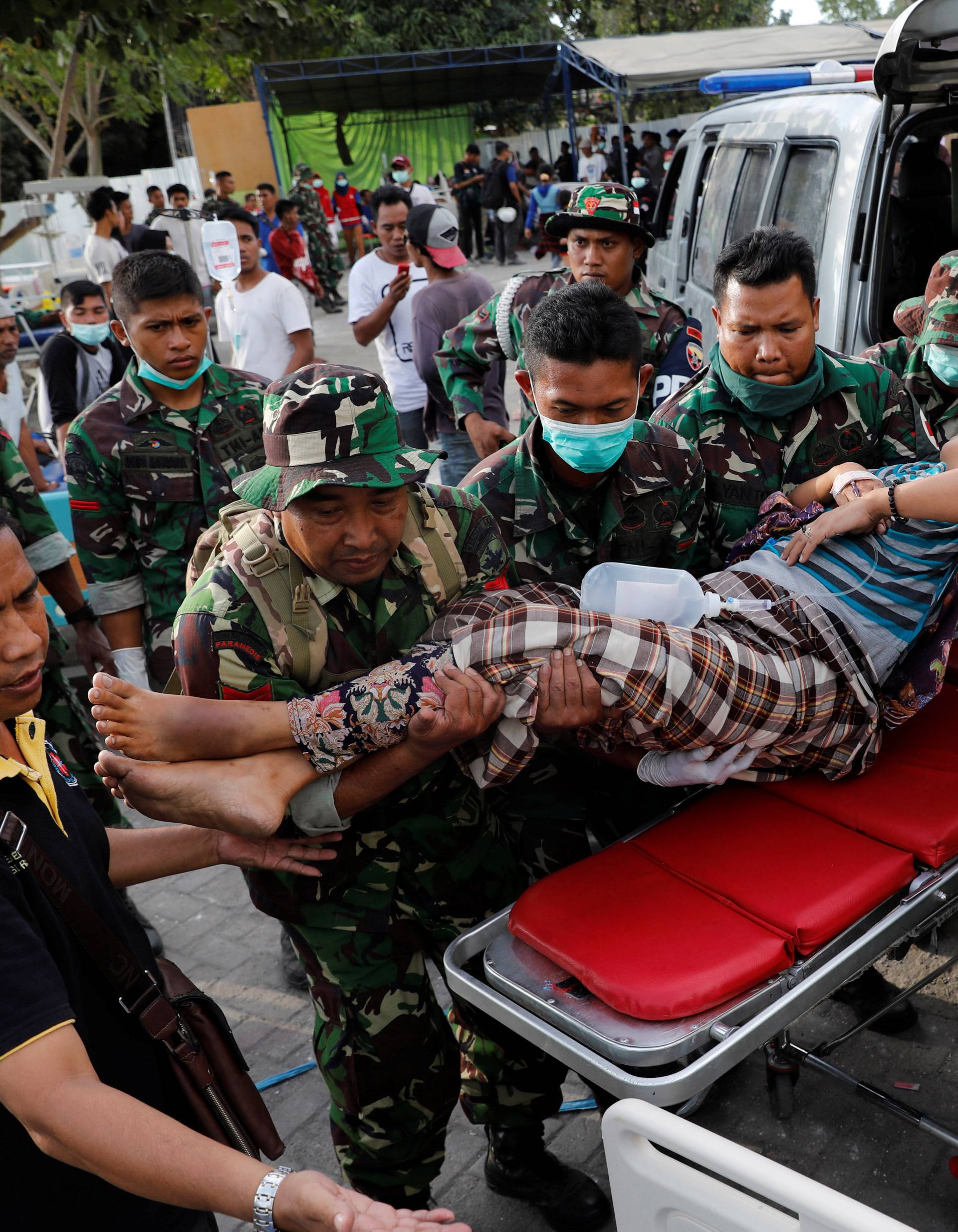 Indonesian soldiers lift up an injured woman after arriving at Tanjung hospital after earthquake hit on Sunday in North Lombok