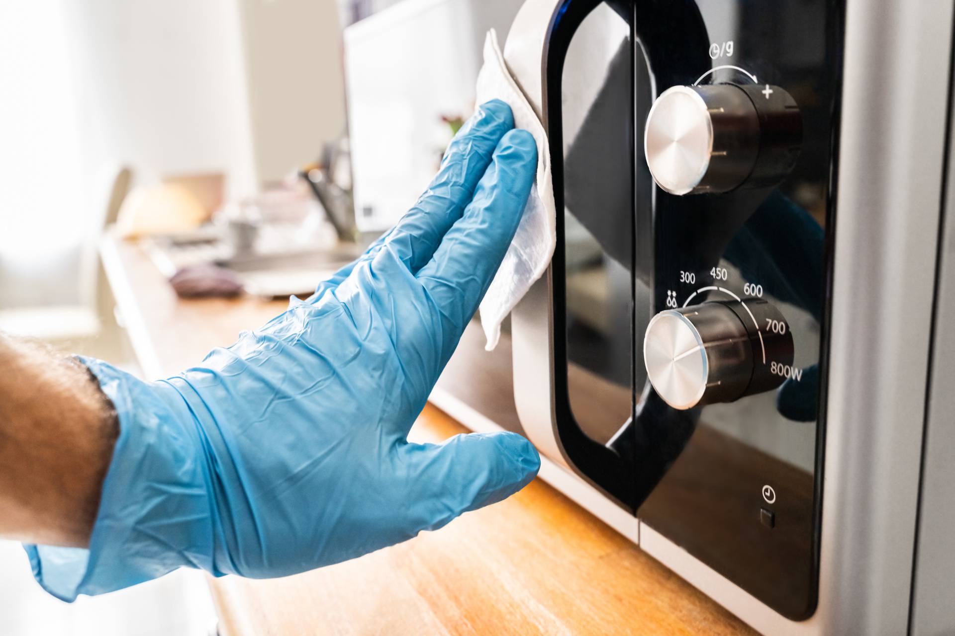 Man Wiping Microwave Oven Handle With Sanitizer