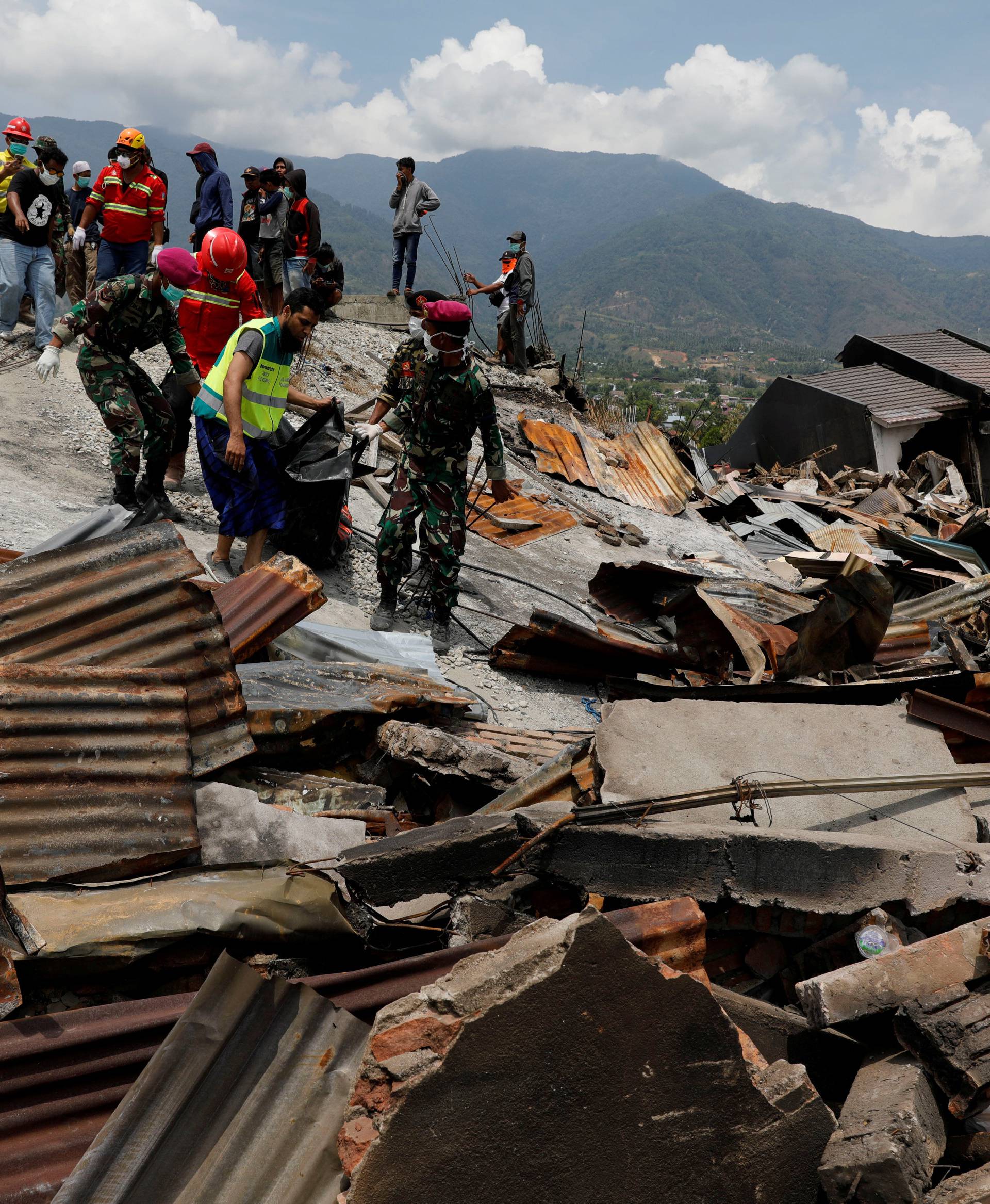 Indonesian soldiers carry a dead body from the ruins of houses after an earthquake hit Balaroa sub-district in Palu