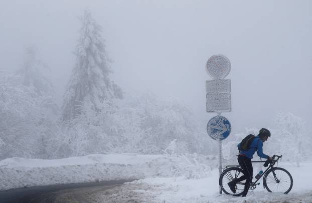 A cyclist pushes his bicycle over the snow-covered Feldberg mountain, outside Frankfurt