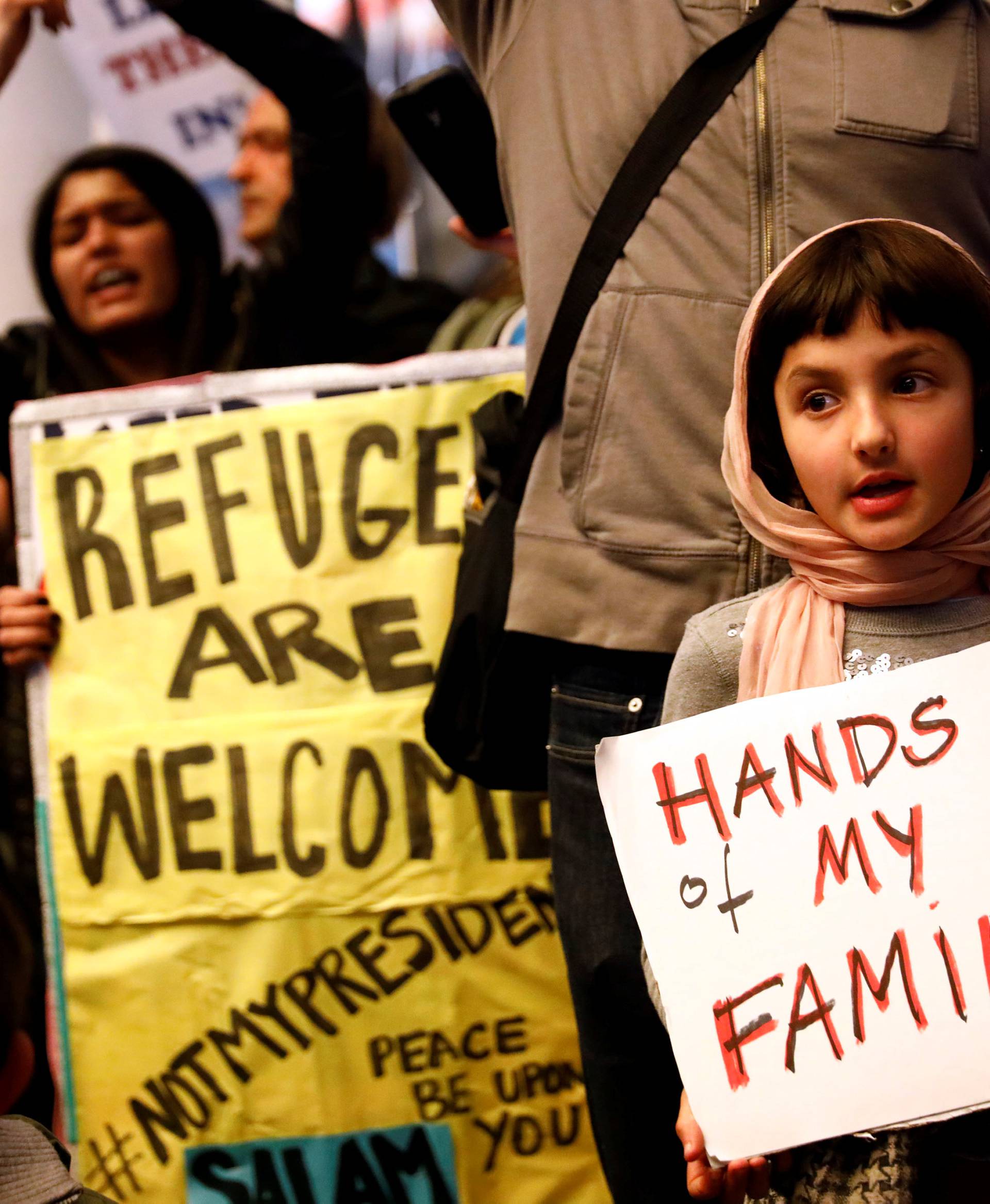 Gurna holds a sign in support of Muslim family members as people protest the travel ban on Muslim majority countries in Los Angeles, California