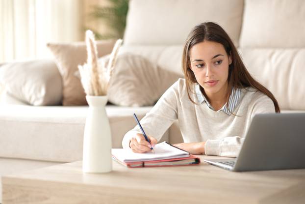 Student,Taking,Notes,Watching,Online,Course,On,Laptop,At,Home
