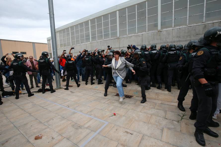 A woman is pushed away by Spanish Civil Guard officers outside a polling station for the banned independence referendum in Sant Julia de Ramis