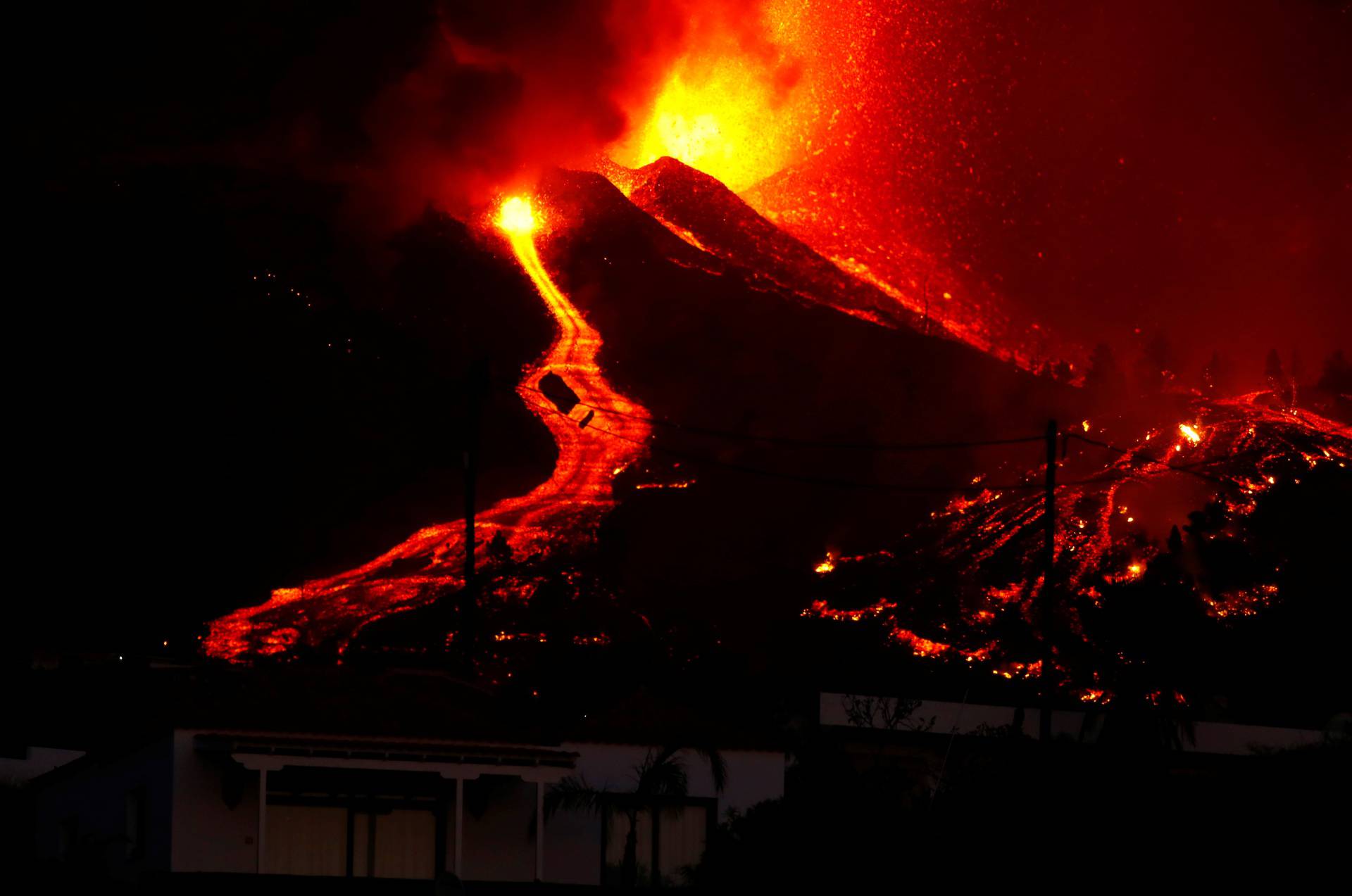 Lava flows next to a housefollowing the eruption of a volcano in Spain