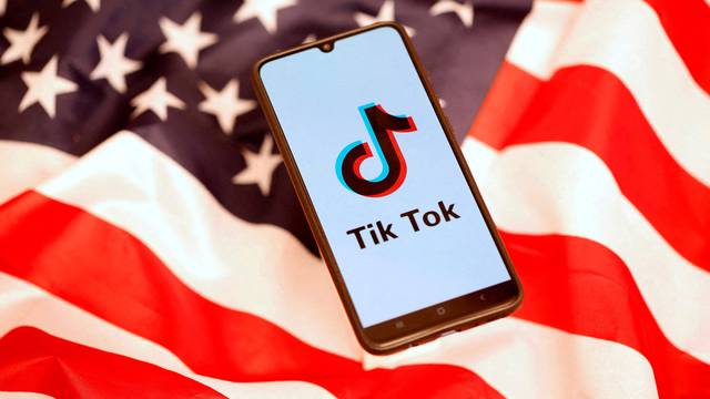 FILE PHOTO: TikTok logo is displayed on the smartphone while standing on the U.S. flag in this illustration