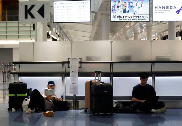 Passengers rest at Haneda Airport as many flights are delayed and cancelled due to Typhoon Dujuan, in Tokyo