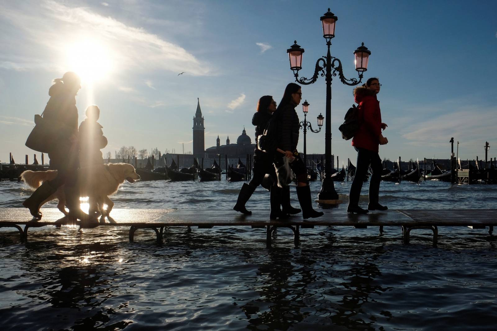 People walk in St. Mark’s Square during high tide in Venice
