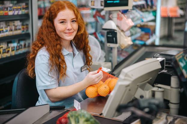 Woman,Cashier,Sitting,Behind,Checkout,And,Working,In,Supermarket.,Female