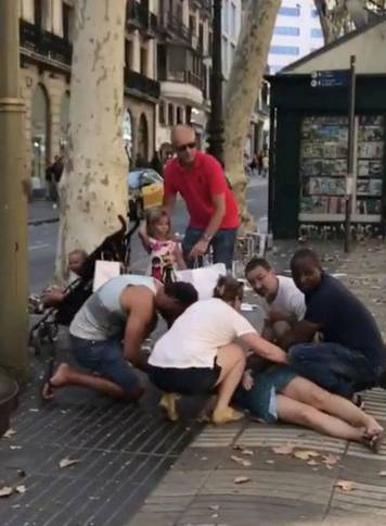 People help an injured woman after a van crashed into pedestrians near the Las Ramblas avenue in central Barcelona