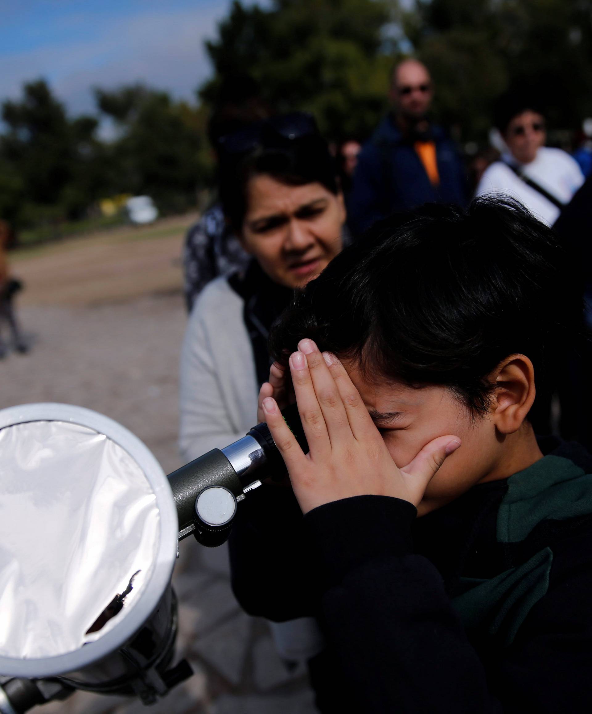 A boy uses a telescope to observe the planet Mercury transit in front of the sun outside Buenos Aires' planetarium