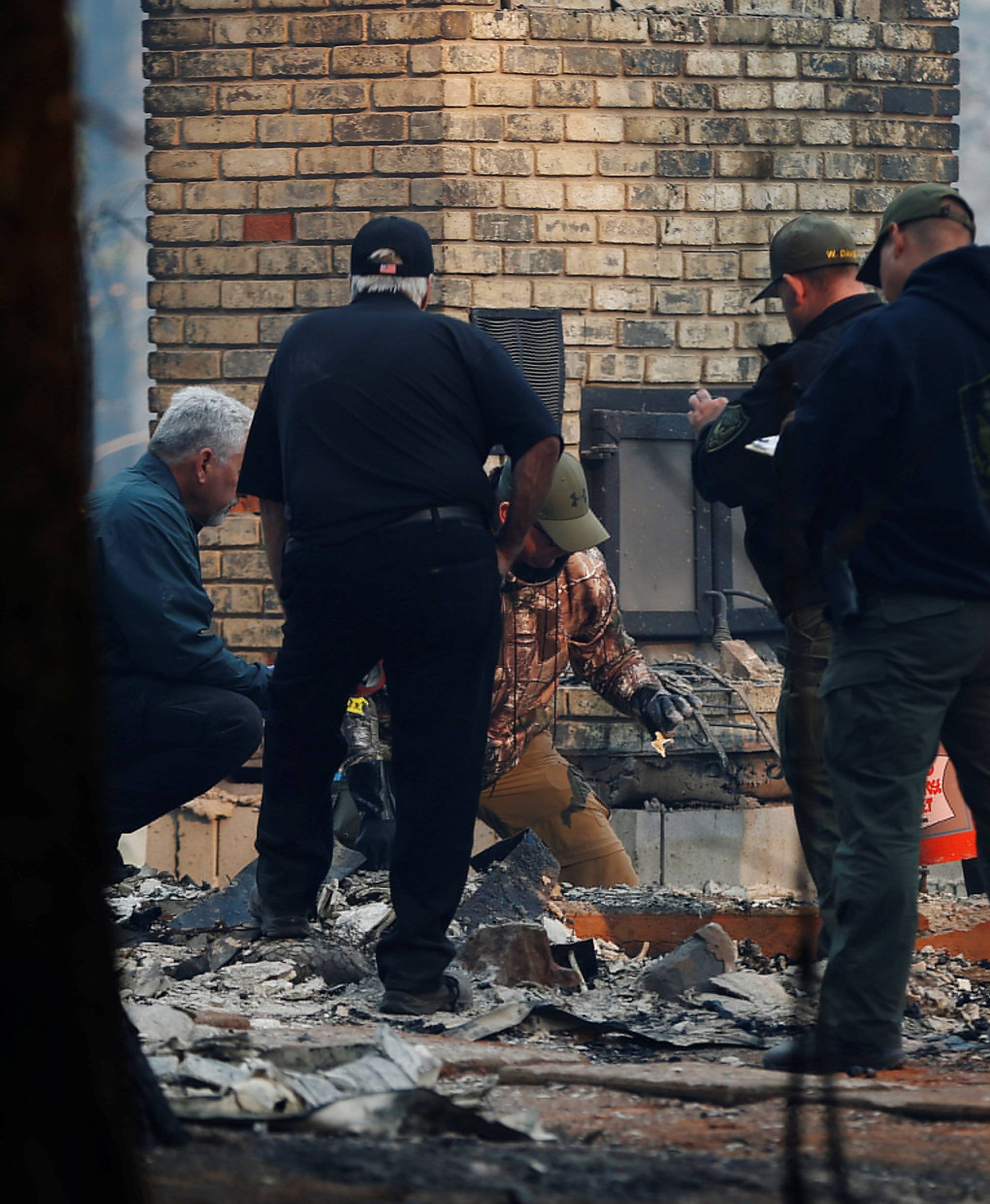 Sheriff deputies retrieve remains of a deceased victim from a home during the Camp Fire in Paradise