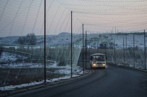 Bus moves along a road covered with anti-drone net in Kharkiv region