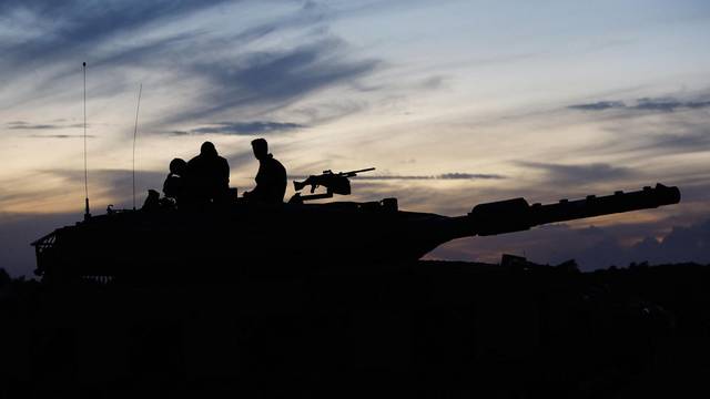 The silhouette of Israeli soldiers as they sit on an Israeli tank near the Israel-Gaza border
