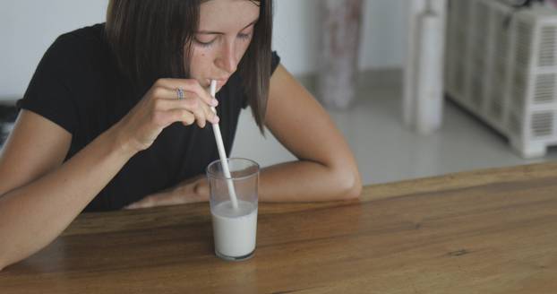 Pretty girl drinks oat multy grain milk from glass straw