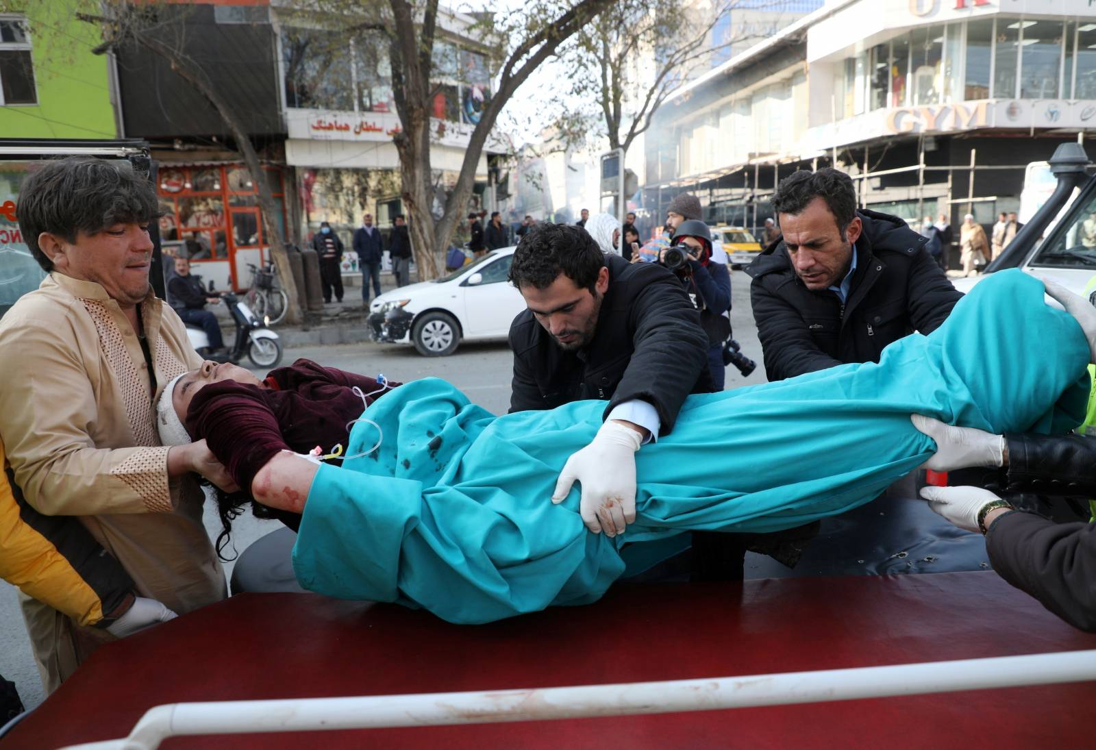 Men carry an injured person to a hospital after rockets hit residential areas in Kabul