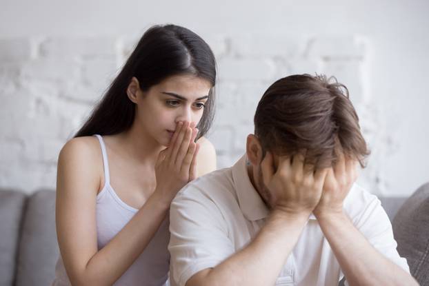 Unhappy young man and woman in quarrel sitting on couch