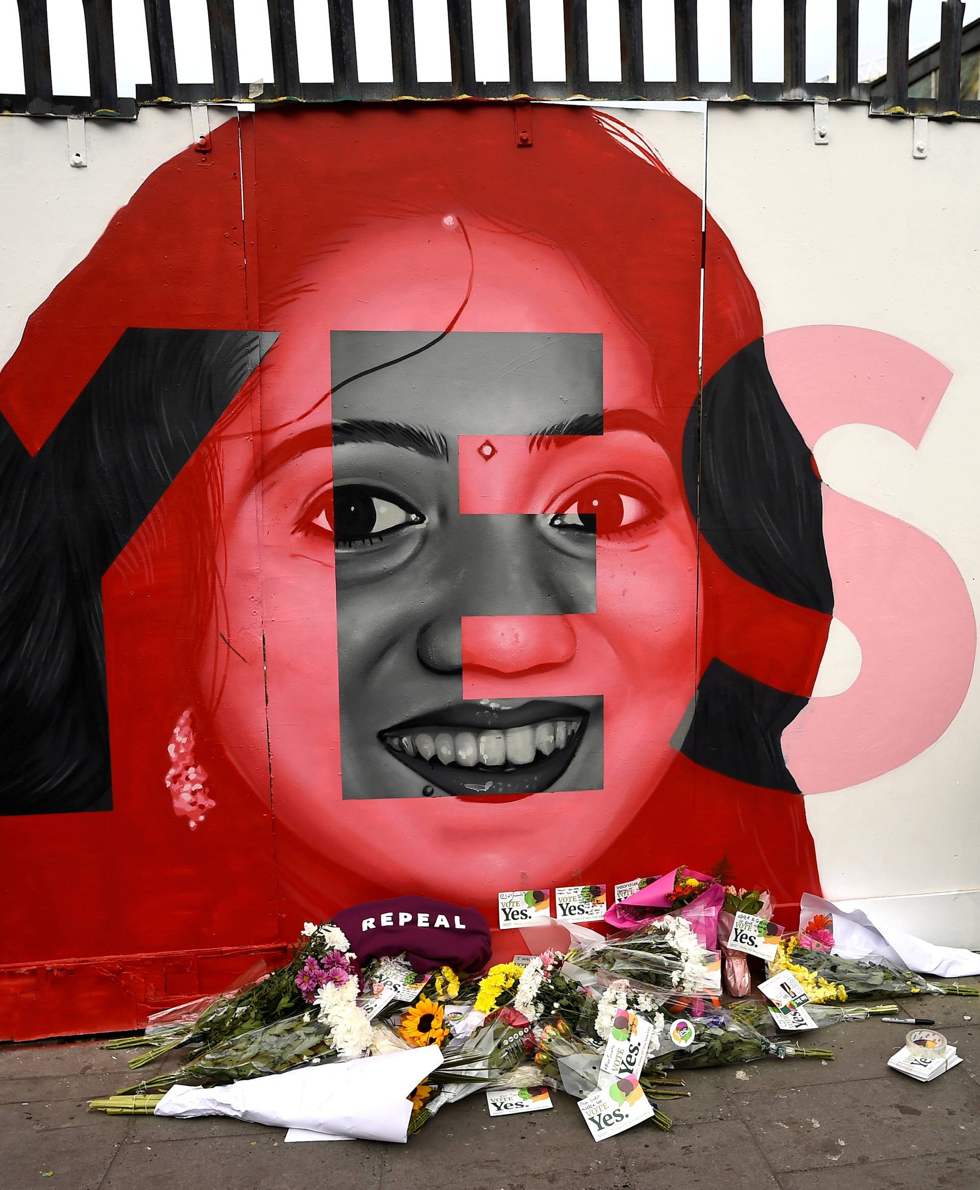 A woman looks at a new mural of Savita Halappanavar with flowers placed beneath it put up on the day of the Abortion Referendum on liberalising abortion laws in Dublin
