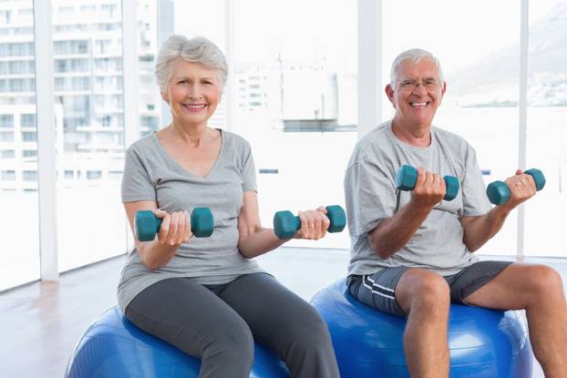 Happy,Senior,Couple,Sitting,On,Fitness,Balls,With,Dumbbells,In